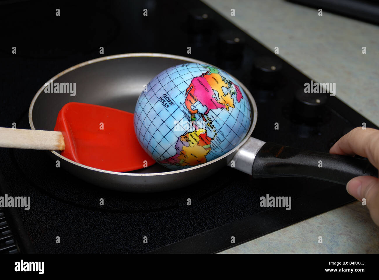 Eine Kugel wird angezeigt, gebraten in einer Pfanne auf eine Herdplatte, stellvertretend für das Konzept der globalen Erwärmung Stockfoto