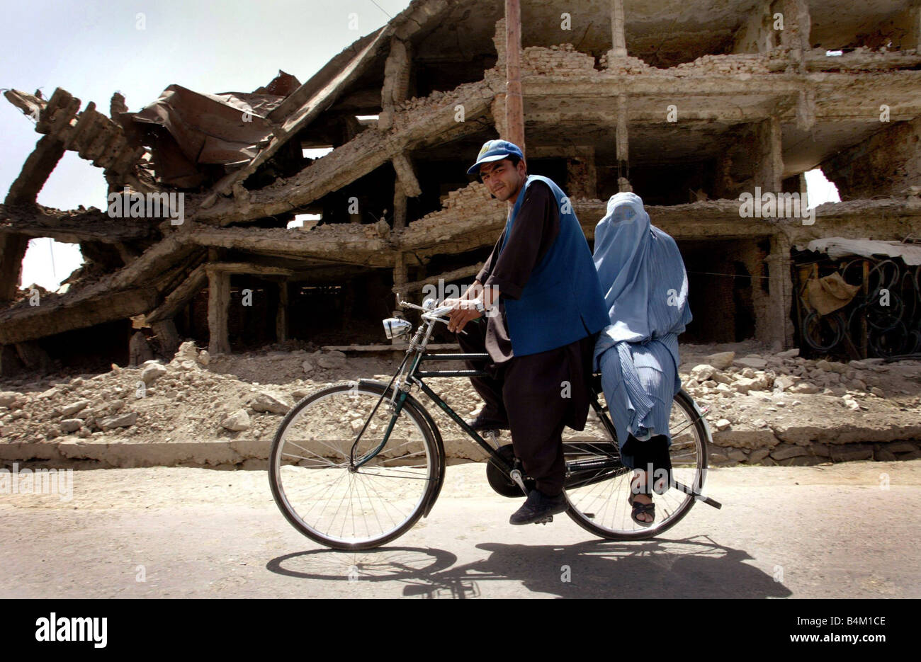 Ein Jahr nach dem 11. September Leben auf der Frontlinie In Kabul Bezirk Kart e Char war die Frontlinie, als die Kämpfe auf seiner Höhe Menschen war versuchen zu überleben und beim Wiederaufbau der Häuser aus den Trümmern, die unser Bild zeigt einen Mann und eine Frau machen sie Weg vorbei an der Zerstörung Stockfoto