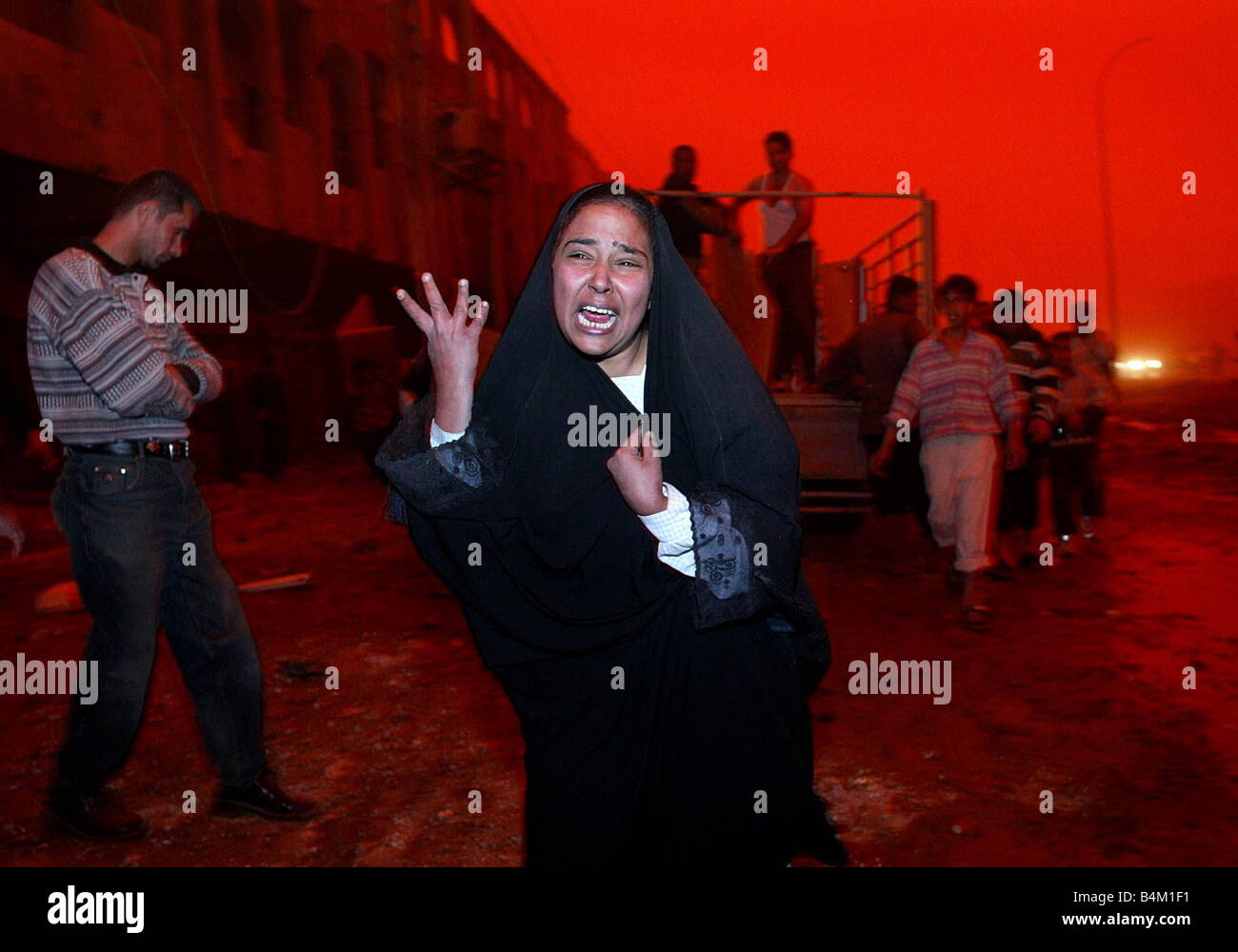 Bagdad im folgenden einen massiven Luftangriff auf dem Gebiet der Al Shahab viele Zivilisten tot unser Bild zeigt verlässt eine unbekannte Frau schreien nach ihrem Ehemann tot in der Explosion gegen den roten glaubte getönten Himmel, verursacht durch die Kombination von schweren Staubstürme und das brennende Öl Feuer rund um Bagdad Stockfoto