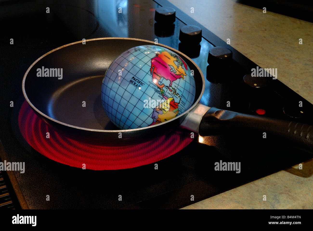 Ein Globus zeigt Braten in einer Pfanne auf eine heiße Herdplatte, die stellvertretend für das Konzept der globalen Erwärmung Stockfoto