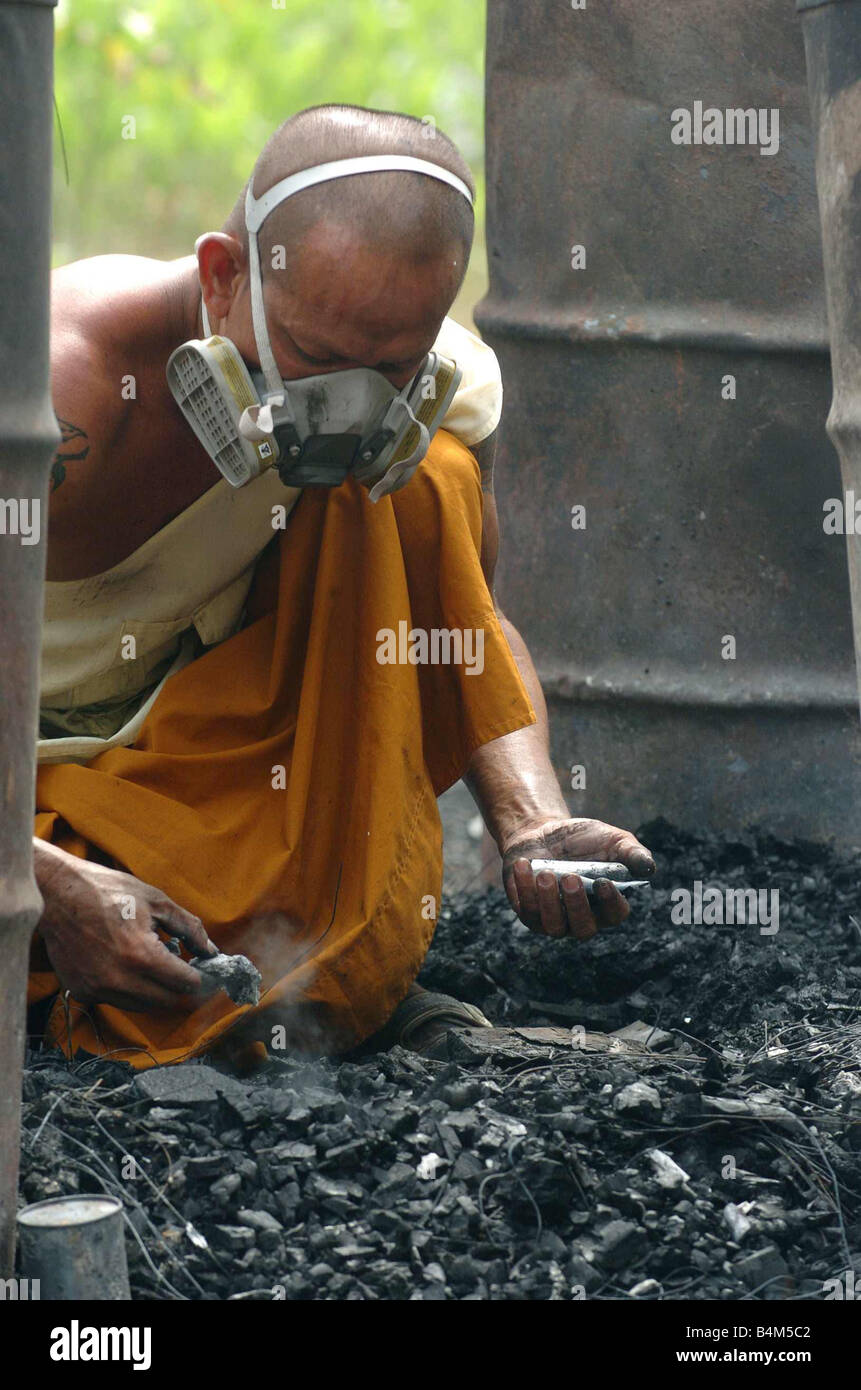 Tsunami Naturkatastrophe Thailand Januar 2005 Mönch steht auf heißen Kohlen von einer anderen Beerdigung sammeln kleine Knochen, die nach der Zeremonie im Wat Kongka Phimook buddhistischen Tempel Mirrorpix geblieben sind Stockfoto