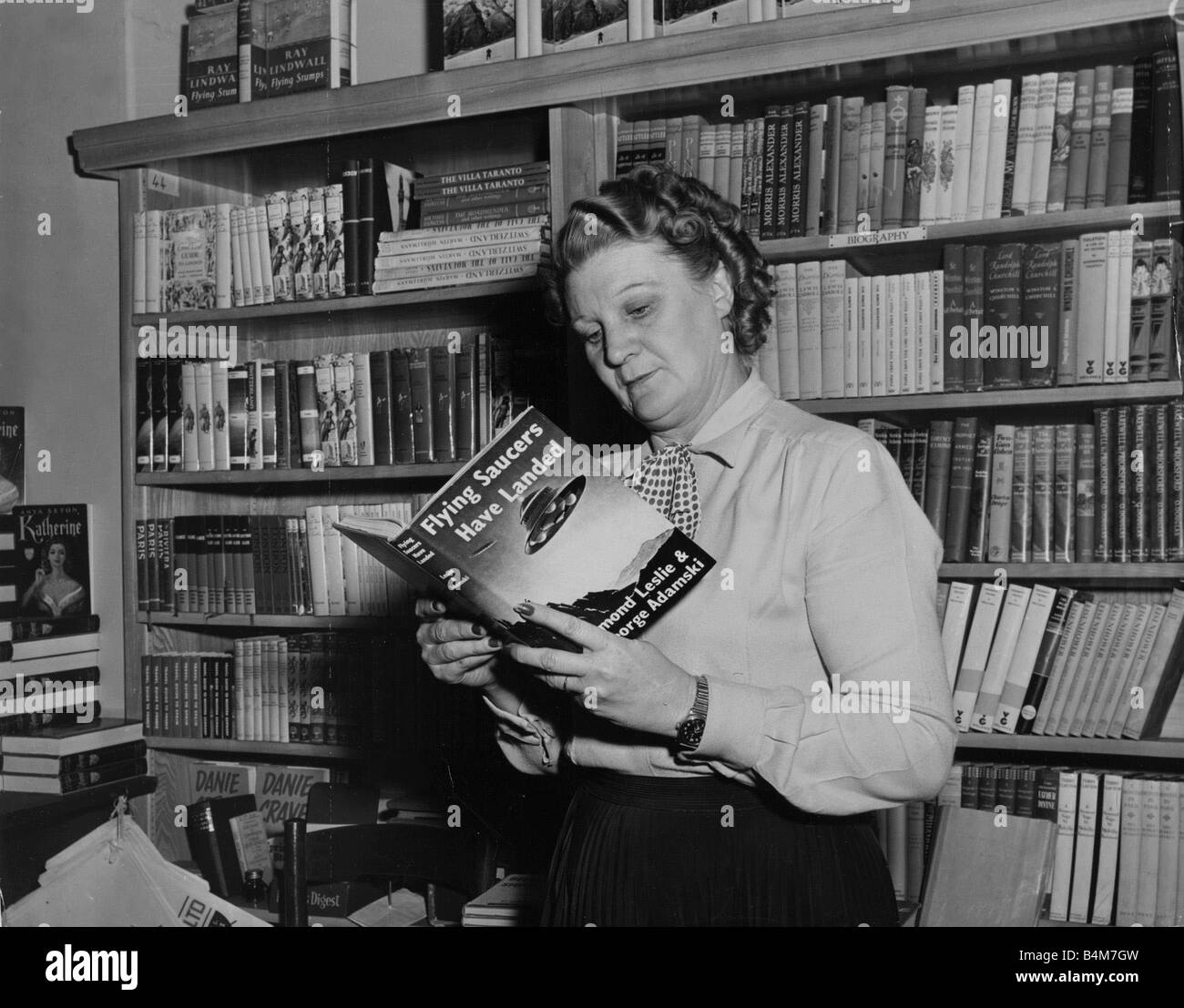 Eine Frau liest ein Buch über fliegende Untertassen der 1950er Jahre Stockfoto