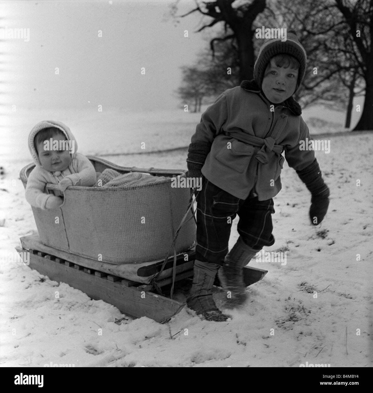 Spaß im Schnee Januar 1960 bekommt 10 Monate alten Susan Torkington von Regent Rd Stockport Werg auf die schneebedeckten Hänge des Lyme Park Disley Cheshire von ihrer 3 Jahre alte Schwester Linda Stockfoto