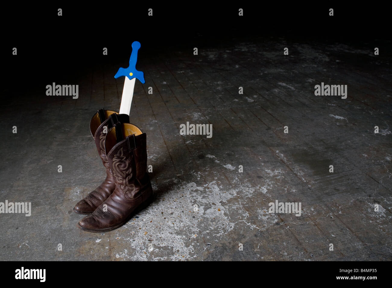 Ein paar getragene Cowboy Stiefel mit einem Kind Spielzeug Schwert ragt, als Symbol der Erwachsene Vorbild für Kinder und emulation Stockfoto