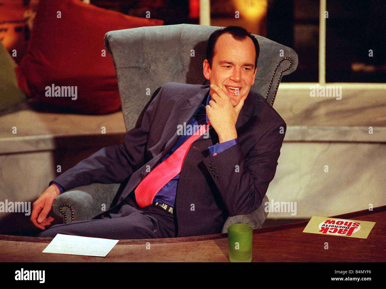 Jack Docherty sitzen im Stuhl neben Schreibtisch im Channel 5 Studio April 1997 Stockfoto
