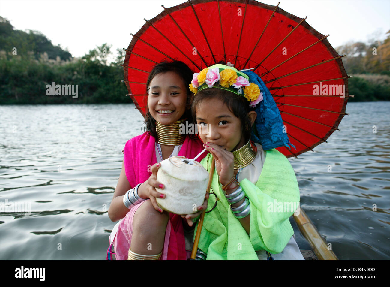 Zwei Longneck Mädchen genießen Sie einen Drink auf einem Boot ca. 300 birmanischen Flüchtlinge in Thailand Mitglieder der indigenen Gruppe bekannt sind als die Longnecks, die größte der drei Dörfer wo live Longnecks Nai Soi genannt befindet sich in der Nähe von Mae Hong Son Stadt longnecks, tragen Metallringe auf den Hals, die das Schlüsselbein nach unten drücken und verlängern dem Hals, sie sind, eine touristische Attraktion besuchen Touristen Nai Soi zu fotografieren die Longnecks und ihr Kunsthandwerk kaufen Die Dörfer sind als menschliche Zoos von Menschenrechtsorganisationen kritisiert. Stockfoto