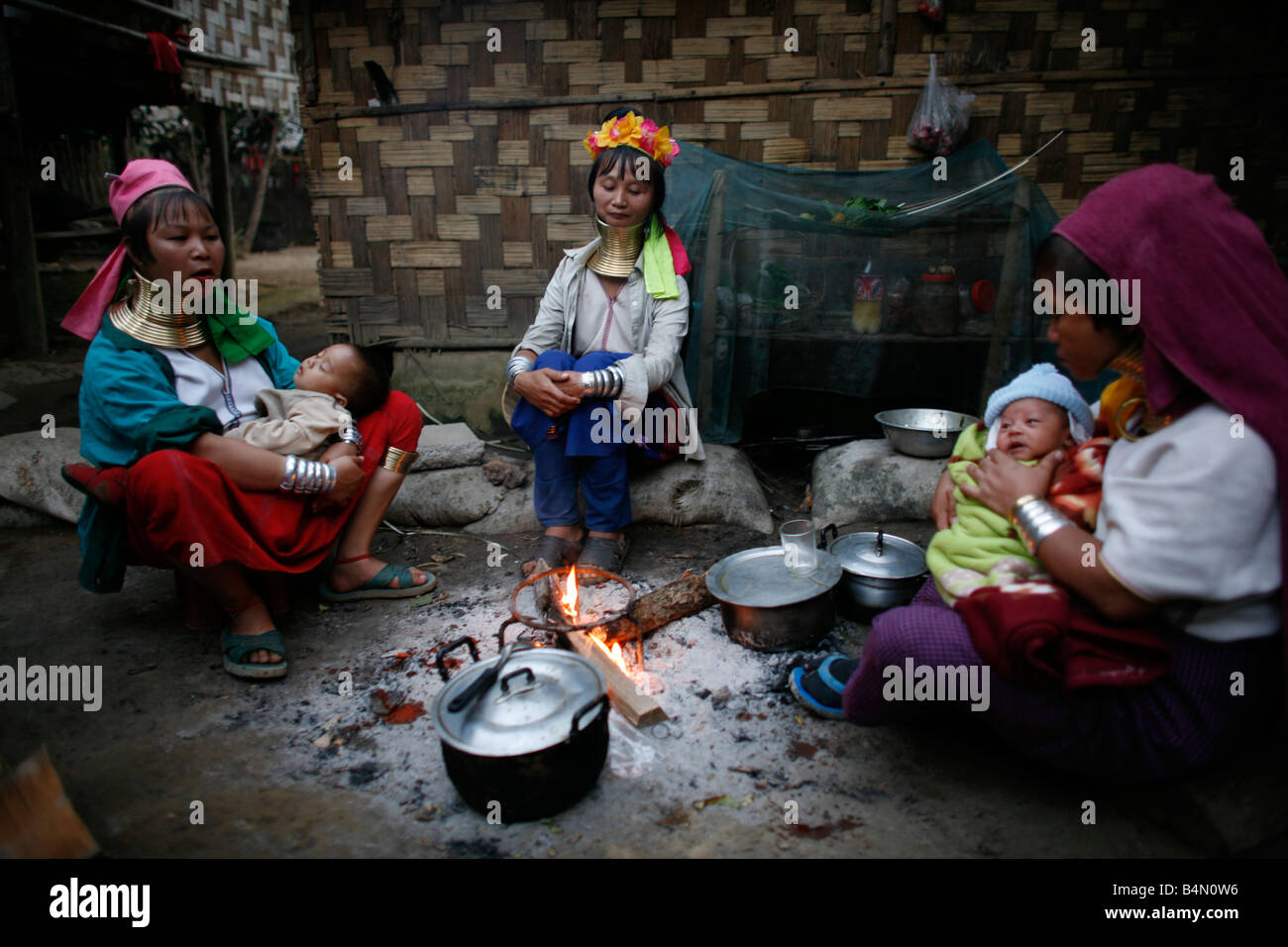 Eine Gruppe von Longneck Frauen sitzen um ein Feuer mit ihren Babys ca. 300 birmanischen Flüchtlinge in Thailand Mitglieder der indigenen Gruppe bekannt sind als die Longnecks, die größte der drei Dörfer wo live Longnecks Nai Soi genannt befindet sich in der Nähe von Mae Hong Son Stadt longnecks, tragen Metallringe auf den Hals, die das Schlüsselbein nach unten drücken und verlängern dem Hals, sie sind, eine touristische Attraktion besuchen Touristen Nai Soi um die Longnecks fotografieren und kaufen Sie ihr Kunsthandwerk, die die Dörfer von Menschenrechtsorganisationen als menschliche Zoos kritisiert werden Stockfoto