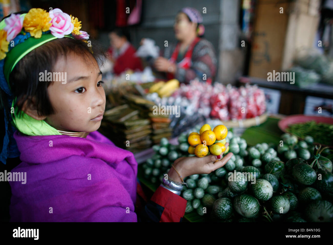 Longneck Mädchen halten Früchte auf einem Markt stehen etwa 300 birmanischen Flüchtlinge in Thailand sind Mitglieder der indigenen Gruppe bekannt als die Longnecks, die größte der drei Dörfer wo live Longnecks Nai Soi genannt befindet sich in der Nähe von Mae Hong Son Stadt longnecks, tragen Metallringe auf den Hals, die das Schlüsselbein nach unten drücken und verlängern dem Hals, sie sind, eine touristische Attraktion besuchen Touristen Nai Soi zu fotografieren die Longnecks und ihr Kunsthandwerk kaufen die Dörfer werden von Menschenrechtsorganisationen als menschliche Zoos kritisiert. Stockfoto