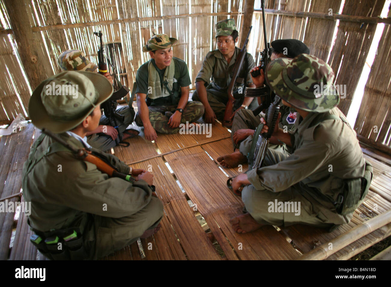 Straflosigkeit Soldaten sitzen in einer Gruppe in einer Hütte In Myanmar Birma Tausende von Menschen siedelten sich in der Nähe von der Grenze als Folge der Unterdrückung in ihrem Heimatland um 200 birmanischen Vertriebenen, in La niedergelassen haben pro Her ein Dorf auf der burmesische Seite der Grenze zu Thailand in der Nähe der thailändischen Stadt von Mae Sot sie weigern sich, die Grenze zu überqueren, weil sie in ihrer Heimat dieser Flüchtlinge bleiben wollen unterstützen die Rebellenbewegung namens Straflosigkeit Karen Nationale Befreiung-Armee betreibt in östlichen Birma Jan 2007 Stockfoto