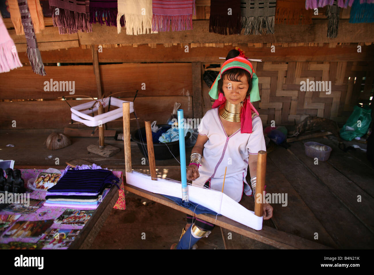 Eine Longneck Frau weben ca. 300 birmanischen Flüchtlinge in Thailand Mitglieder der indigenen Gruppe bekannt sind als die Longnecks, die größte der drei Dörfer wo live Longnecks Nai Soi genannt befindet sich in der Nähe von Mae Hong Son Stadt longnecks, Metall tragen Ringe auf den Hals, die das Schlüsselbein fertig drücken und verlängern den Hals sind sie eine touristische Attraktion, die Touristen besuchen Nai Soi zu fotografieren die Longnecks und kaufen ihre Handarbeiten, die, denen die Dörfer von kritisiert werden Organisationen der menschlichen Rechte als menschliche zoos Stockfoto