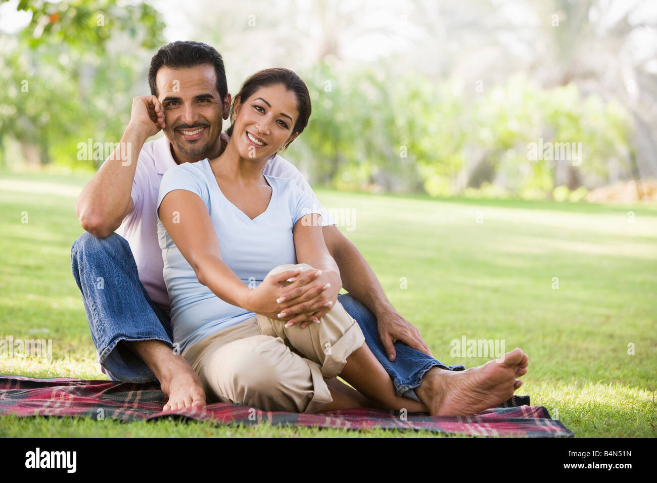 Paar sitzt draußen im Park lächelnd (Tiefenschärfe) Stockfoto
