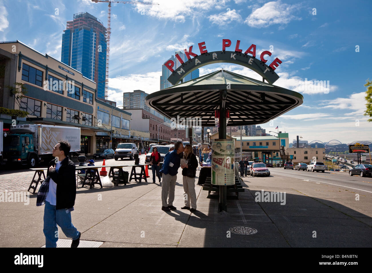 Paar zu stoppen, um einen Kuss bei einem Spaziergang in der Innenstadt von Seattle Washington unter Bushaltestelle Tierheim Werbung in der Nähe der Pike Place Market Stockfoto