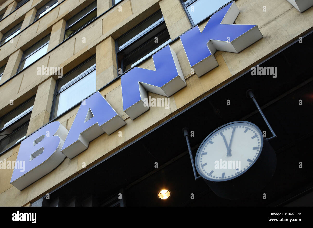 BANK-Schild an einem Gebäude und eine Uhr zeigt 12:05 Stockfoto