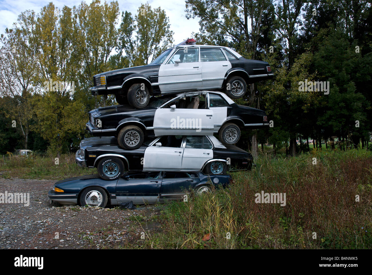 Schrottplatz: Einen alten Pontiac ist Teil einer Skulptur gemacht zu schauen, wie ein Stapel von alten Polizeiautos Stockfoto