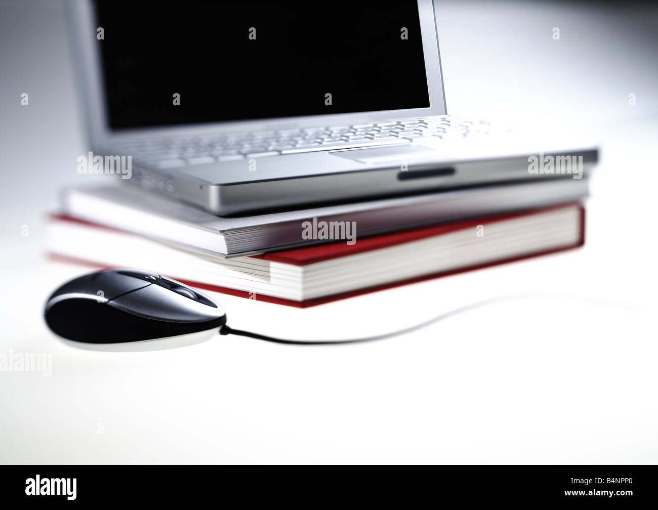 Offenen Laptop-Computer und Silber Schwarz Maus auf Stapel Bücher weißer Hintergrund Stockfoto