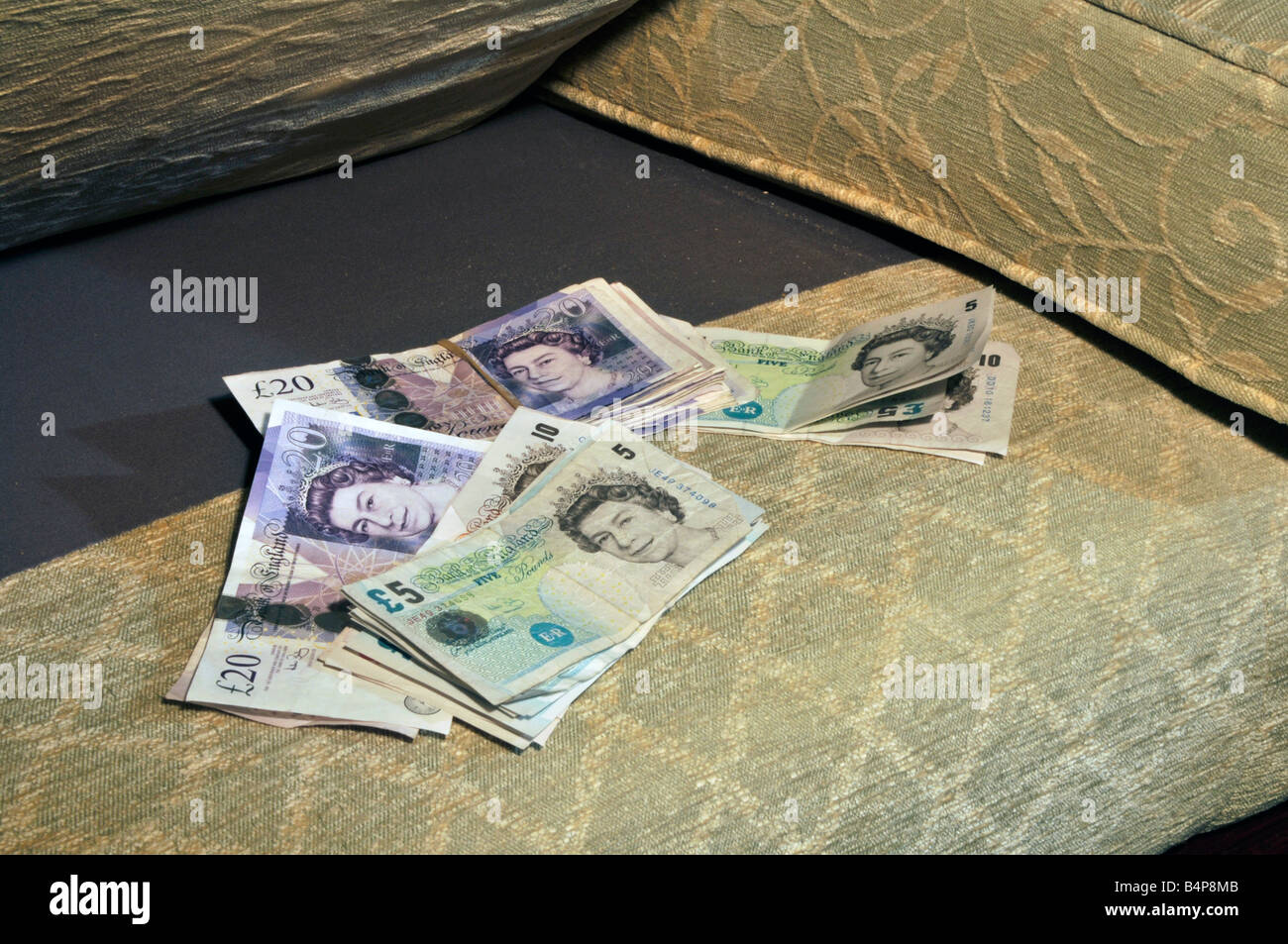 Geld zu sparen, verschiedene Werte Pfund Bargeld bank Notes gespeichert in Innenräumen Versteck für Banknoten unter Sofa Sessel Kissen England Großbritannien Stockfoto