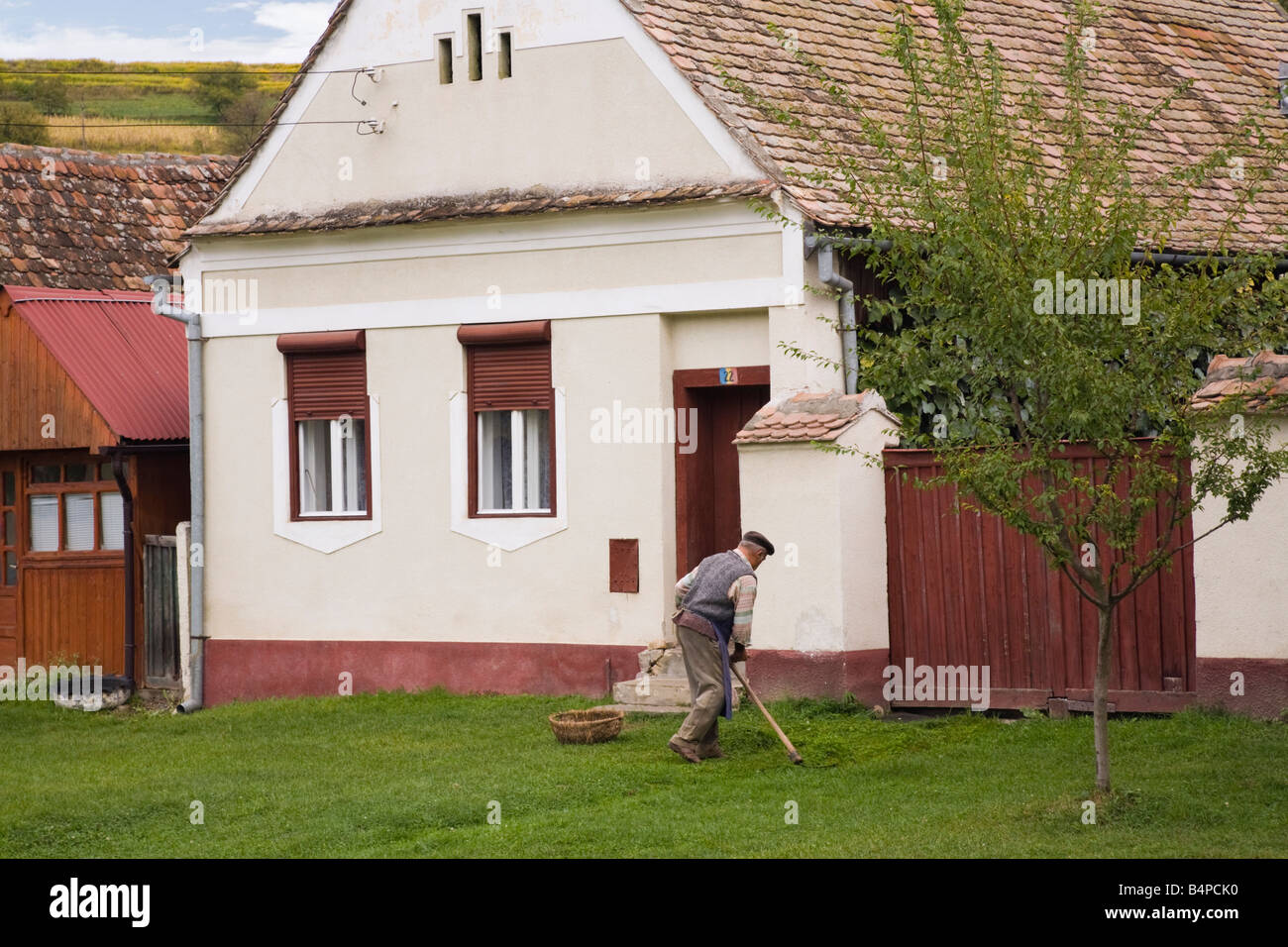 Birthälm Siebenbürgen Rumänien Europa Mann mit der Sense zu mähen außerhalb traditionelles Haus im Dorf Stockfoto