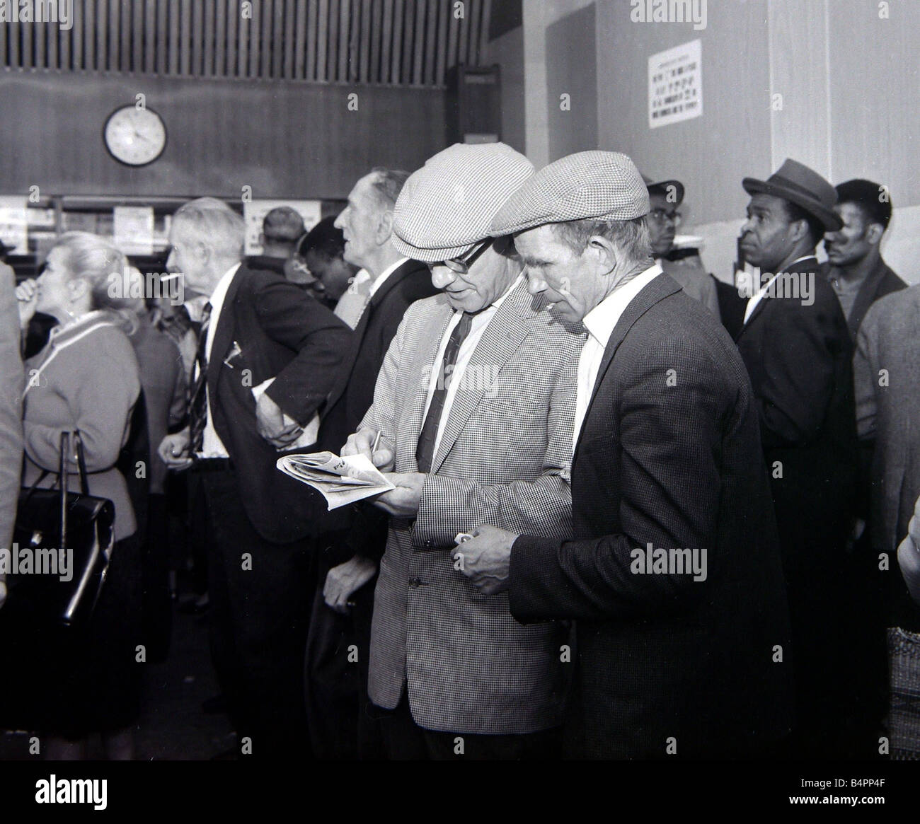 Ein beschäftigt Szene in einem Wettbüro mit Börsenspekulanten Schlange, um Wetten Minuten vor dem Start des Epsom Derby Juni 1962 zu machen Stockfoto