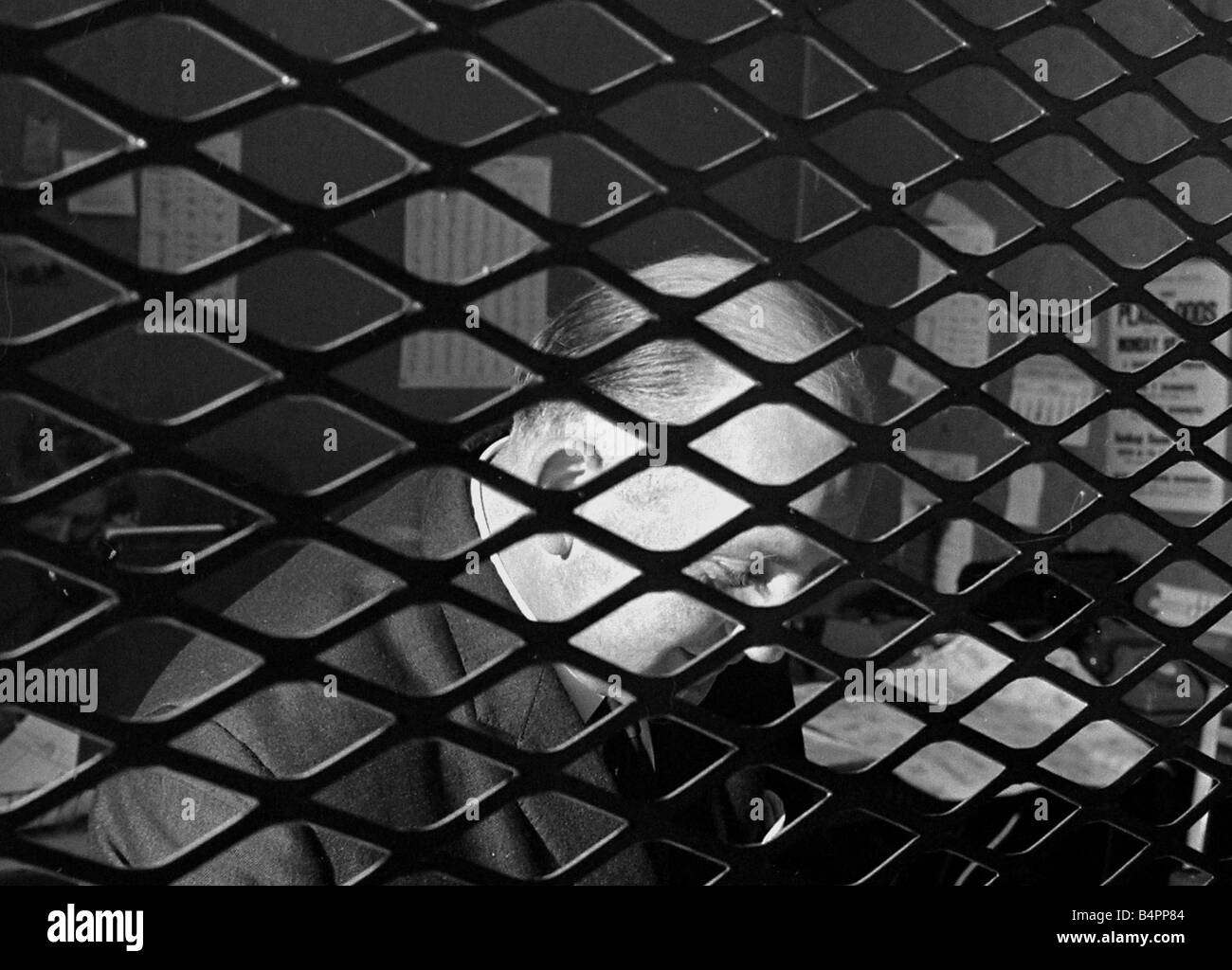 Buchmacher Sidney Glanz im Bild durch die Gitteröffnungen im Inneren seine Wettbüro in der Isle Of Man kein Bargeld Wetten darf in seinem Geschäft Juni 1969 Stockfoto