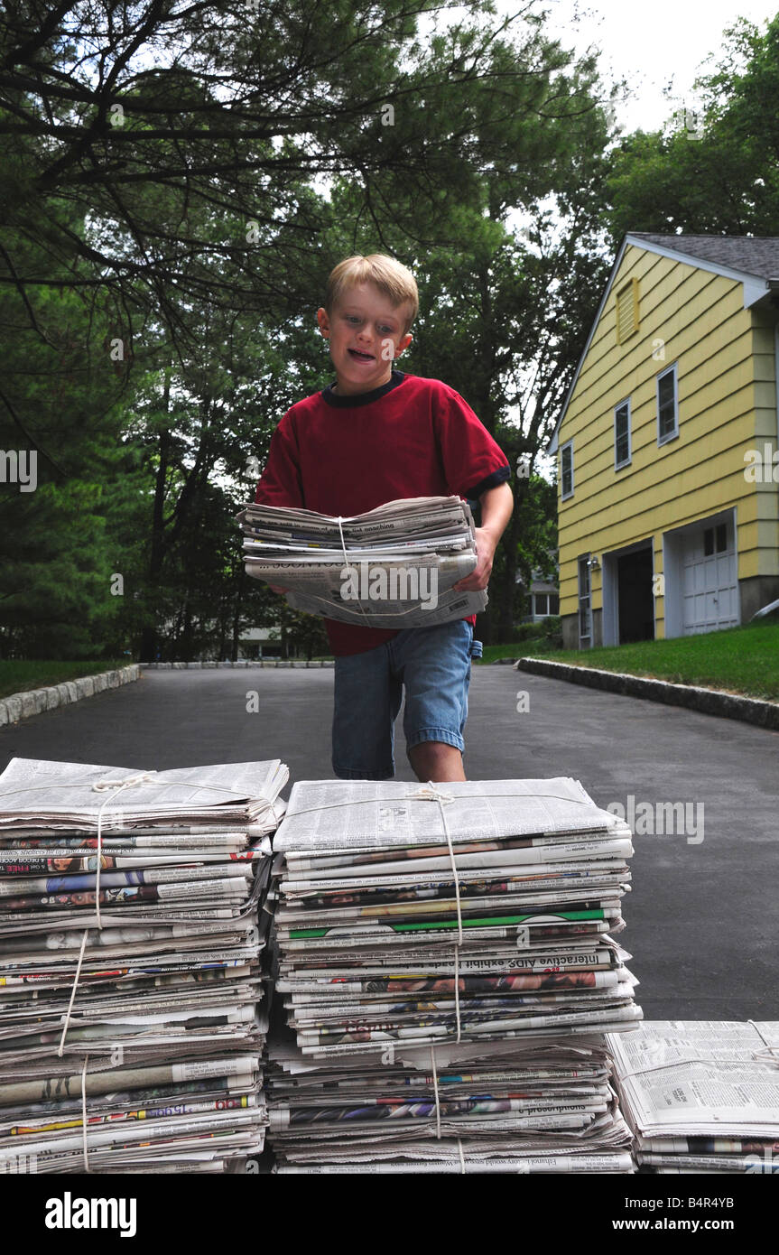 Kleiner Junge Stapeln Zeitungen für Papier-recycling Stockfoto