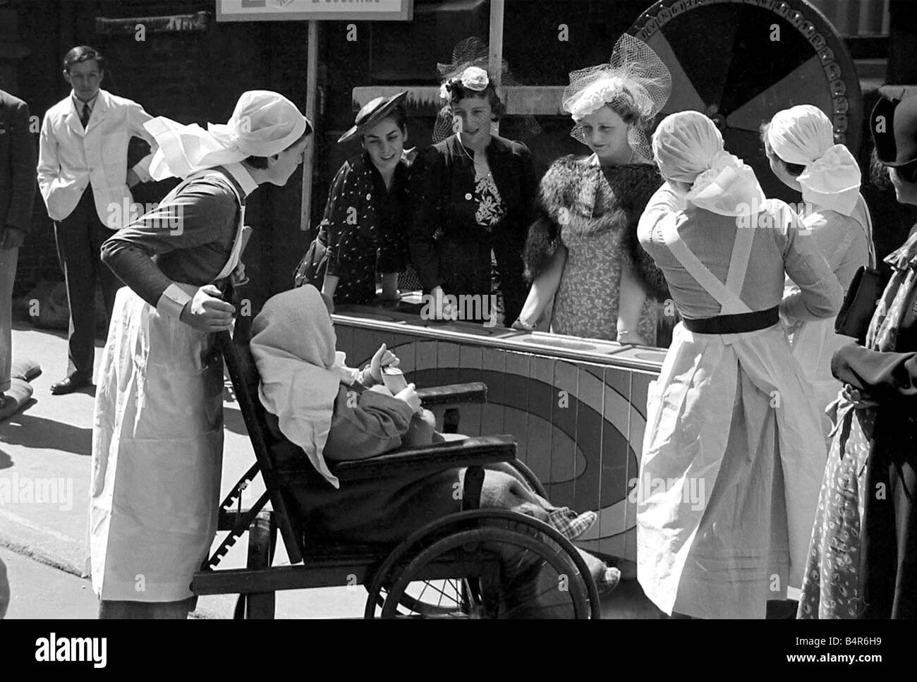 Krankenschwestern, schieben ein Kind im Rollstuhl um faire Barts ca. 1938 Stockfoto