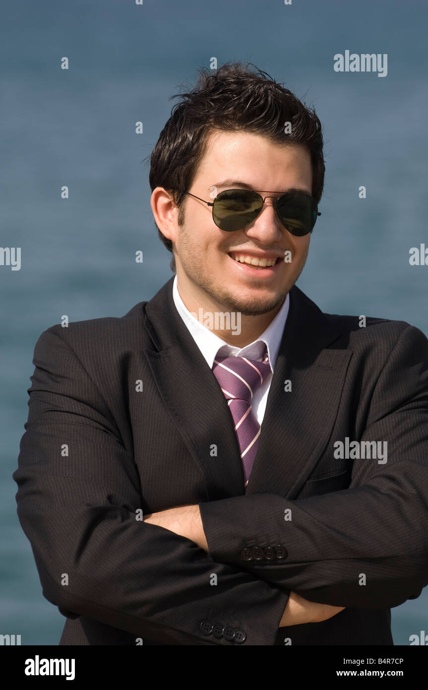 Glücklich Geschäftsmann tragen Anzug und Sonnenbrille am Meer verschränkten Armen Stockfoto