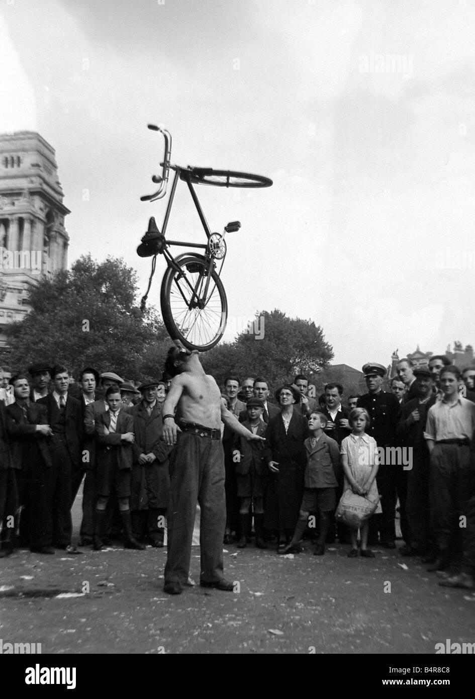 Eine Straße Entertainer am Tower Hill in London Ausgleich ein Fahrrad mit seinem Mund beobachtet von einer Menge von Zuschauern Circa 1935 Stockfoto