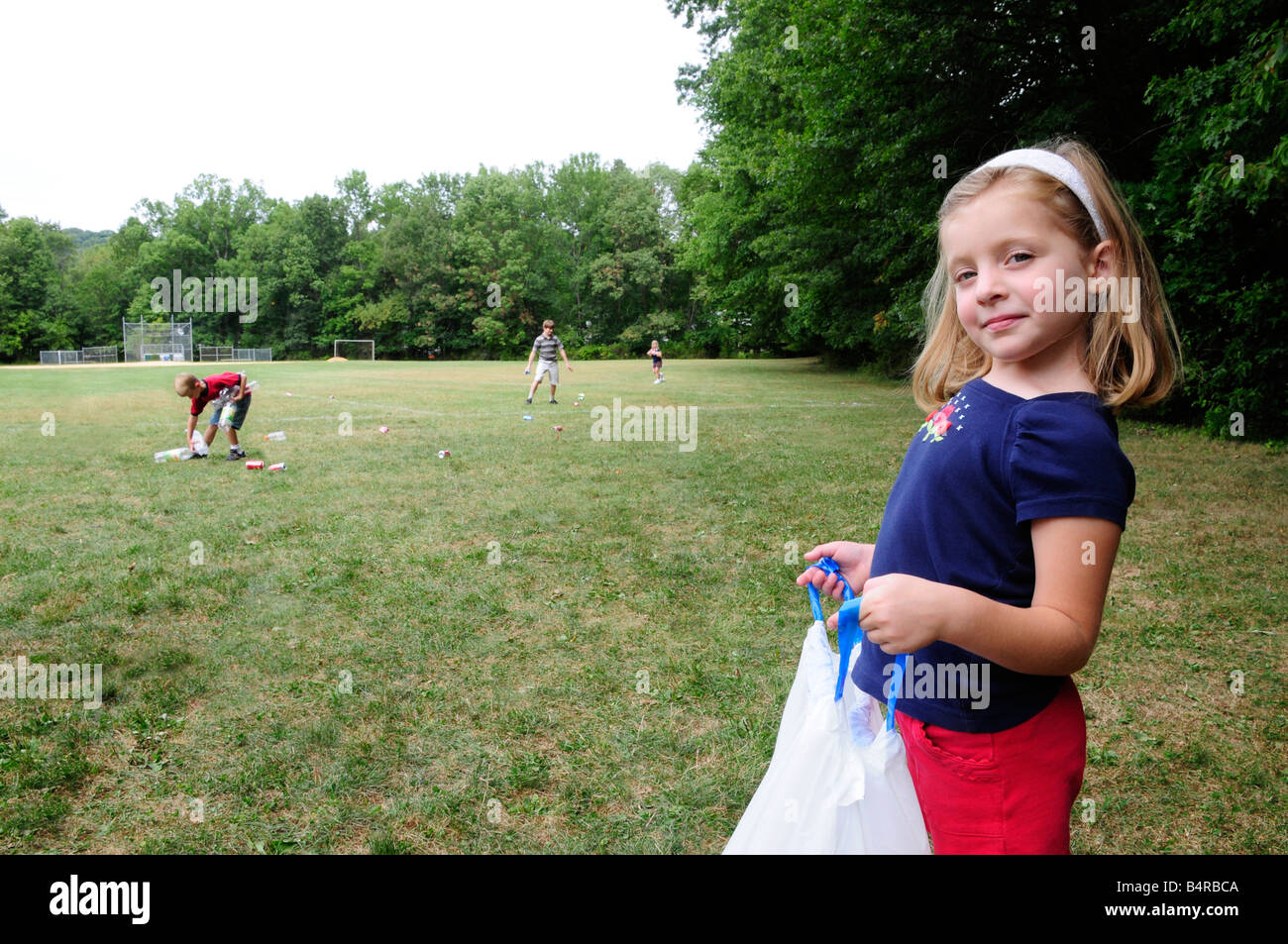 Mädchen hält einen Müllsack helfen Gemeinschaftswerk Service Abholung recycelbar Wurf in einem Park oder Feld Stockfoto