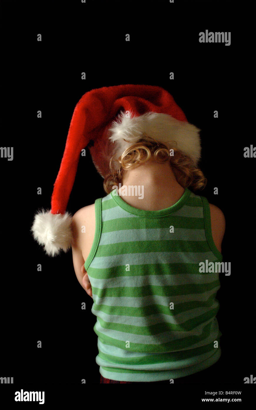 Weiße Mädchen trägt eine rote Weihnachtsmütze und grün gestreifte Weste, wandte sich von der Kamera. Stockfoto