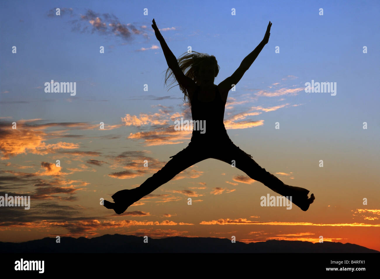 Silhouette einer springenden Frau bei Sonnenuntergang Stockfoto