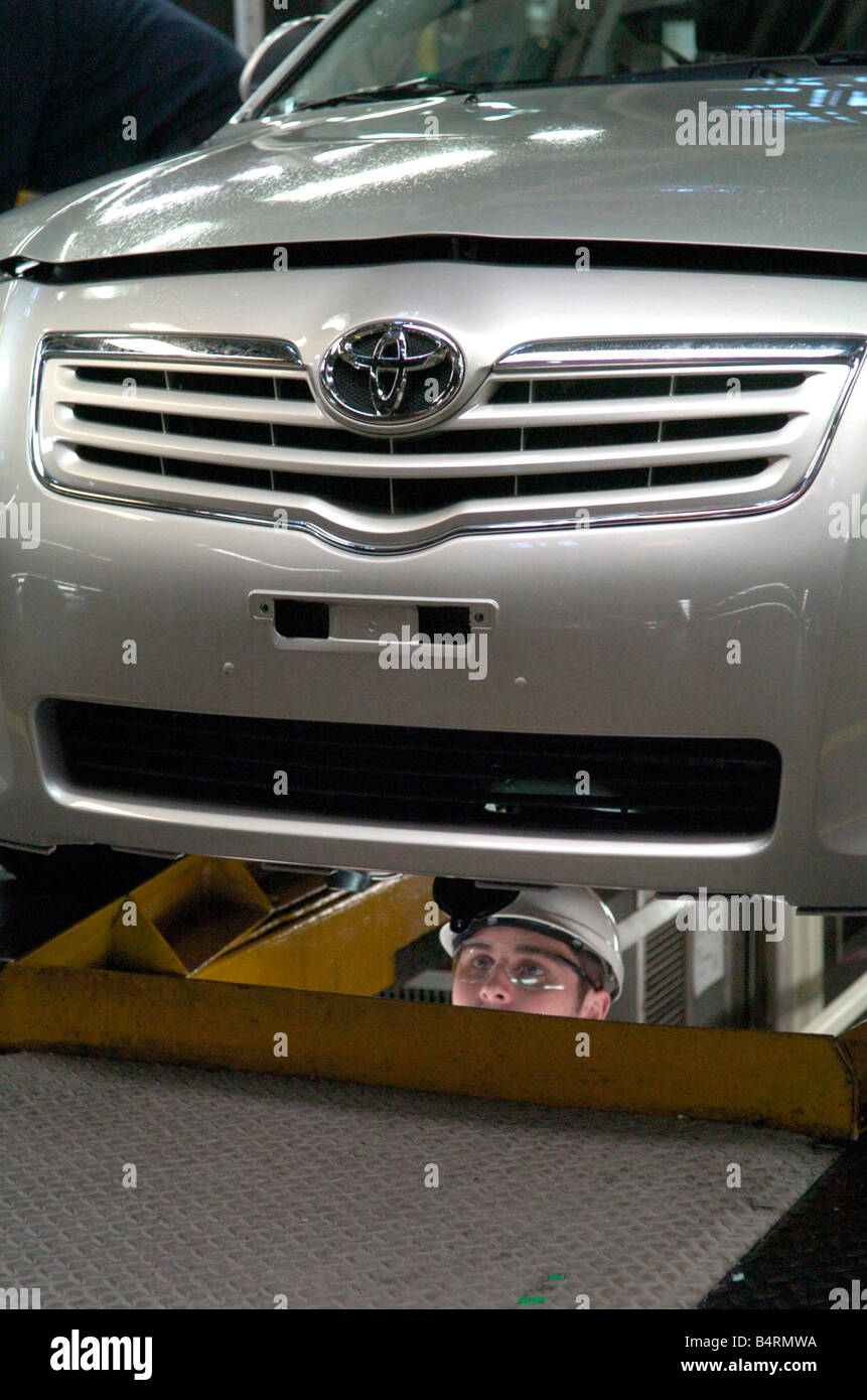 Ein Arbeiter in der Toyota-Fabrik in Derby inspiziert die Unterseite eines Avensis Autos. Stockfoto