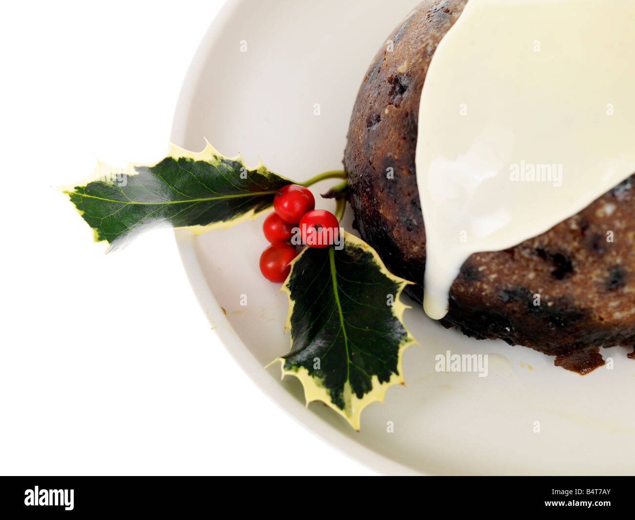 Eine traditionelle Weihnachtspudding mit Holly und Rote Beere traditionellen Dekorationen und gekrönt mit Brandy Sauce auf Teller serviert gegen Weiße Stockfoto