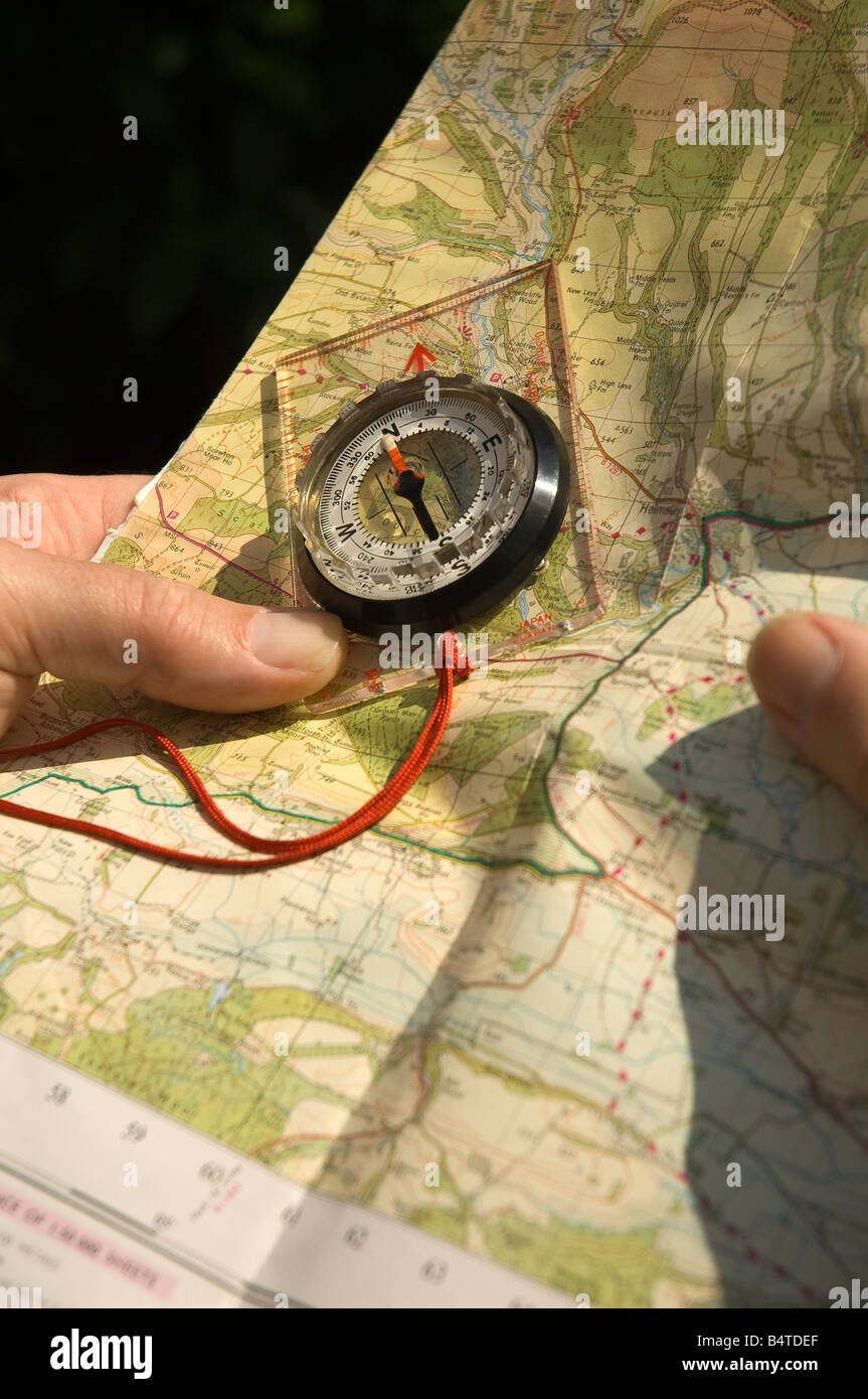 Überprüfen der Wegbeschreibung einer Wanderroute auf einer Papierkarte und einem Kompass aus nächster Nähe Stockfoto
