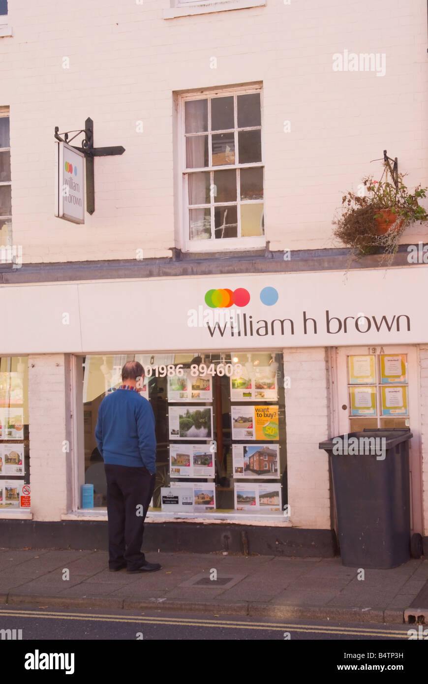 Älterer Mann sucht im William h braun Immobilienmakler Fenster für Häuser zum Verkauf Stockfoto