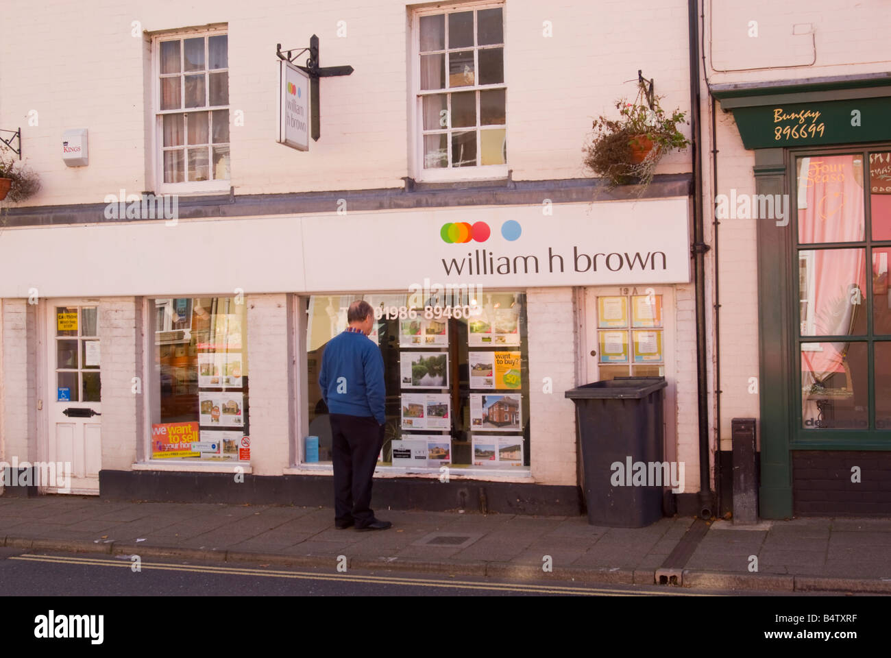 Älterer Mann sucht im William h braun Immobilienmakler Fenster für Häuser zum Verkauf Stockfoto