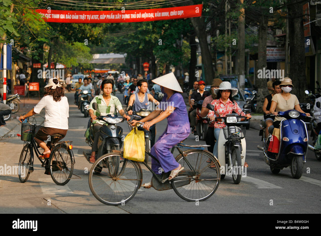 Frau mit Bambushut auf Fahrrad an Kreuzung, Hanoi, Vietnam Stockfoto