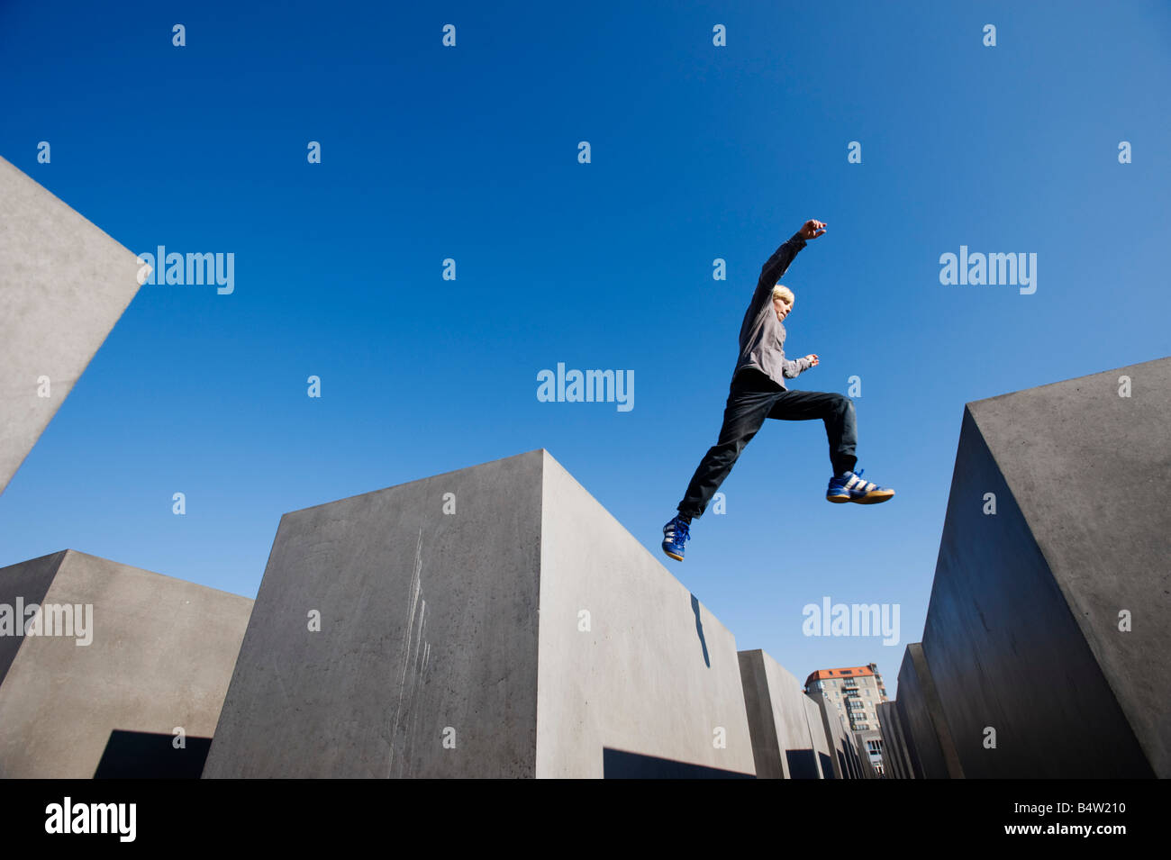 Junge springt zwischen Betonblöcken am Denkmal für die ermordeten Juden Europas im Zentrum Berlins Stockfoto