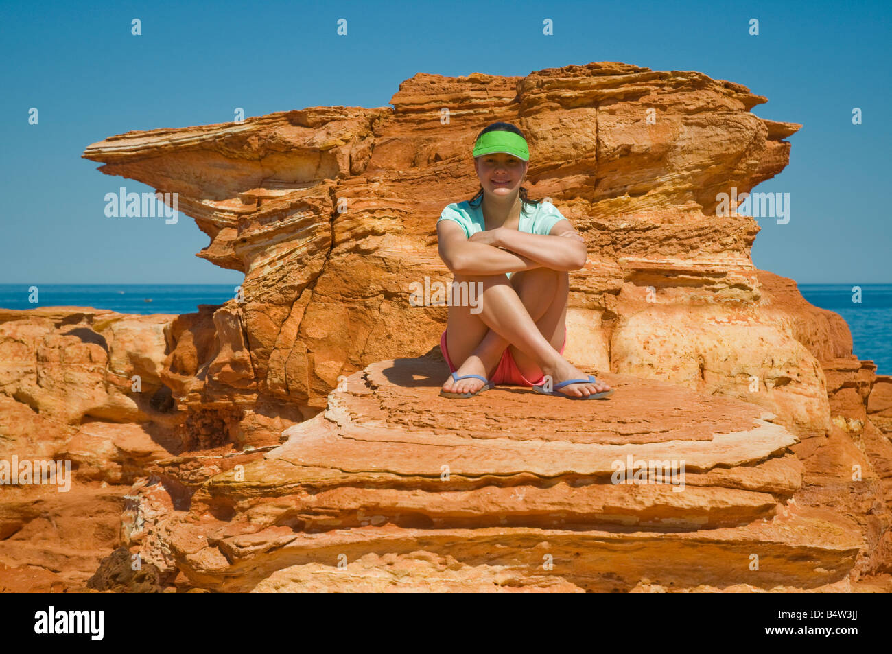 Ein junger Tourist stellt sich gegen die bunten roten geologischen Formationen am Gantheaume Point in der Nähe von Broome Western Australia Stockfoto