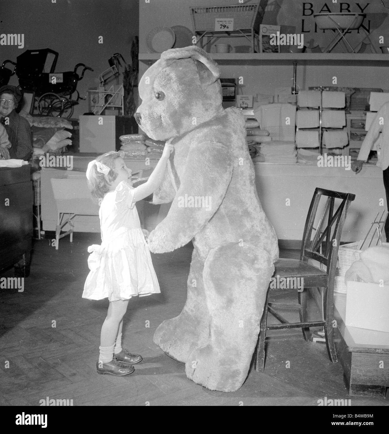 Rosemary Allerton kitzelt die riesigen Teddybär unter dem Kinn im Bereich Spielzeug-Abteilung von Lewis Ltd. in Leeds; Dec. 1953; Neg-N Stockfoto