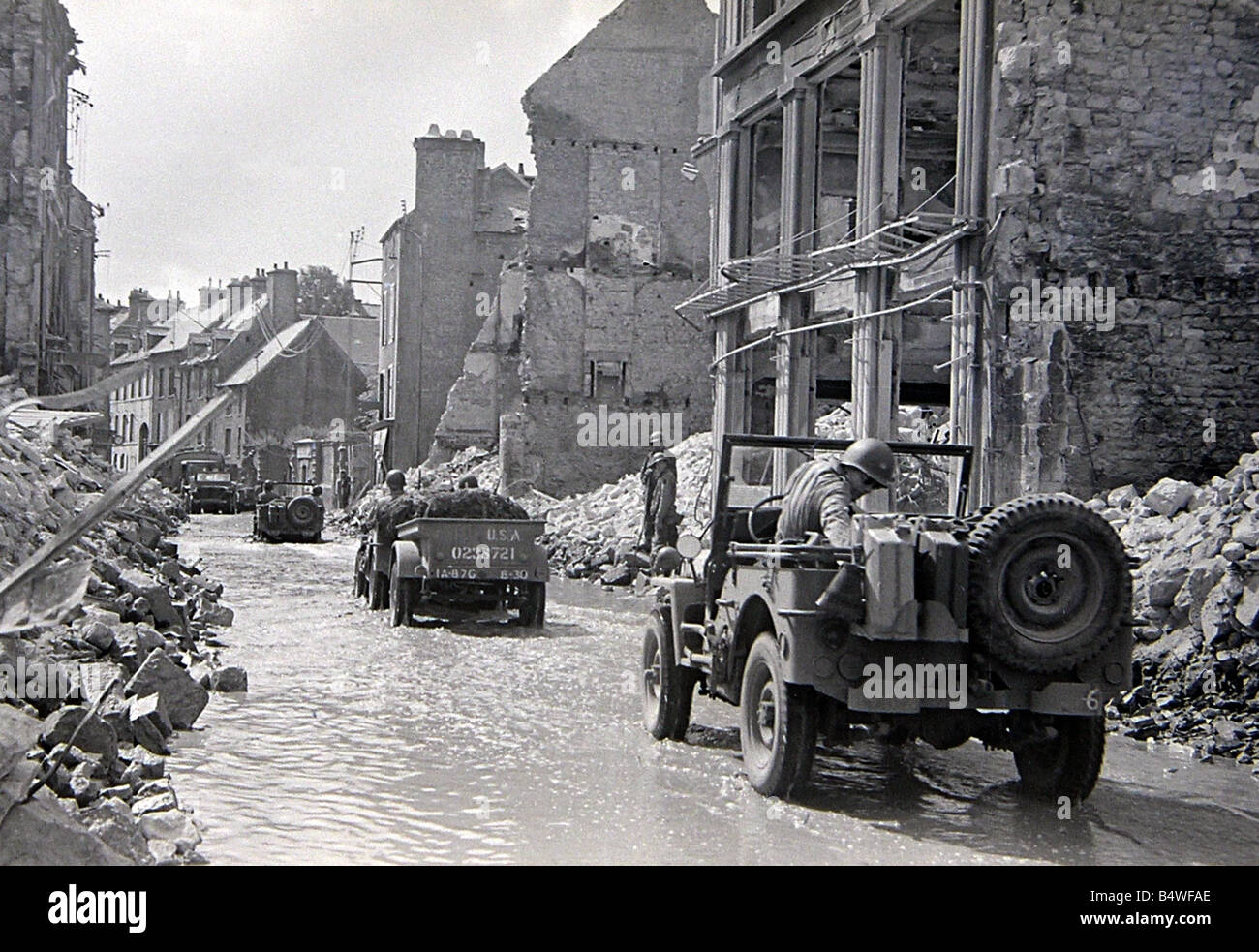 Amerikanische Truppen in Jeeps, die ihren Weg durch eine Bombe beschädigt Normandie Stadt in Nordfrankreich kurz nach dem D-Day Landungen begonnen die alliierte Invasion des Kontinents im Weltkrieg 2. Juli 1944 Stockfoto