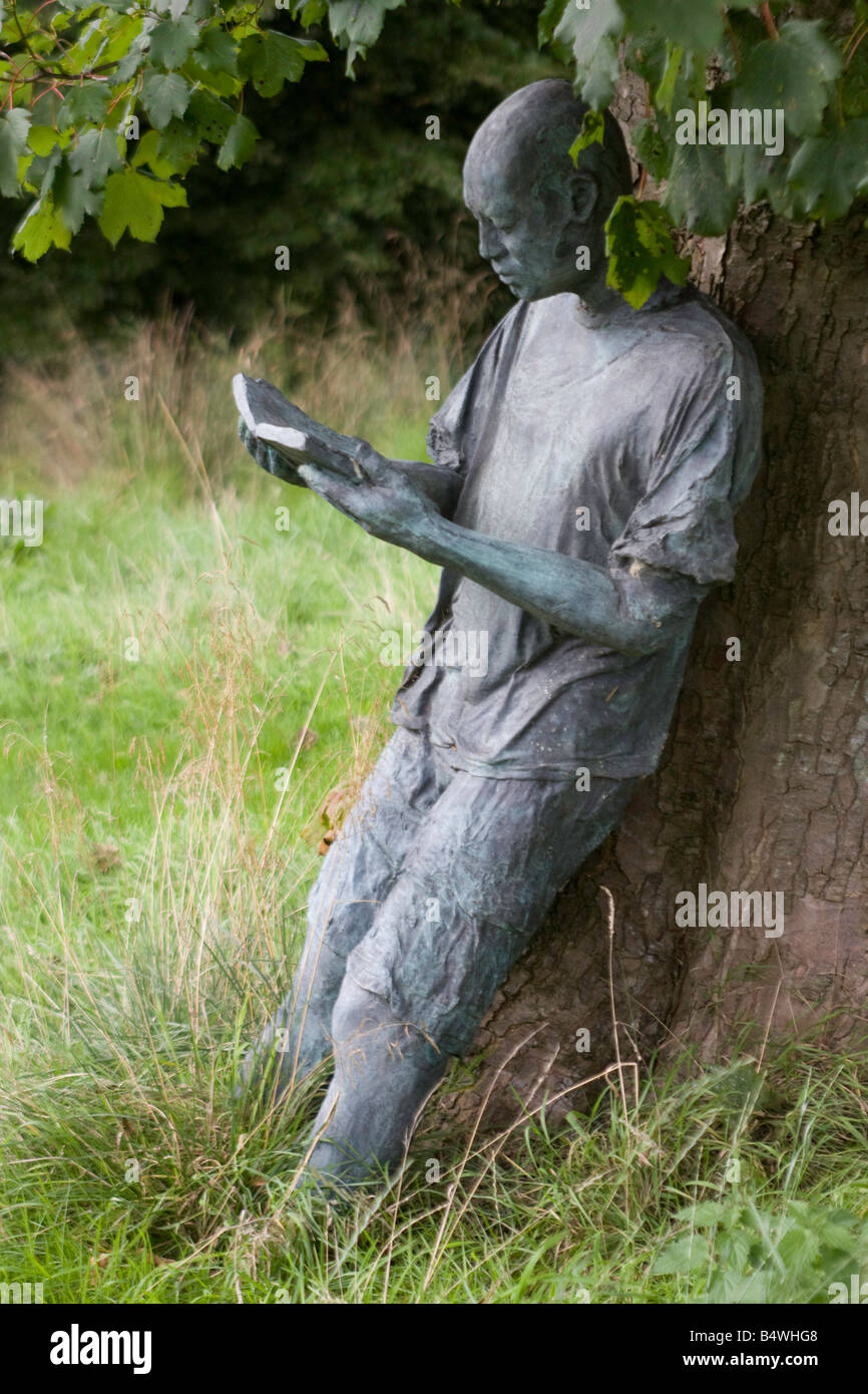 Leben Größe Bronze Statue des männlichen Figur lehnte sich gegen einen Baum, ein Buch des tschechischen Künstlers Olbram Zoubek.Garden Funktion Stockfoto