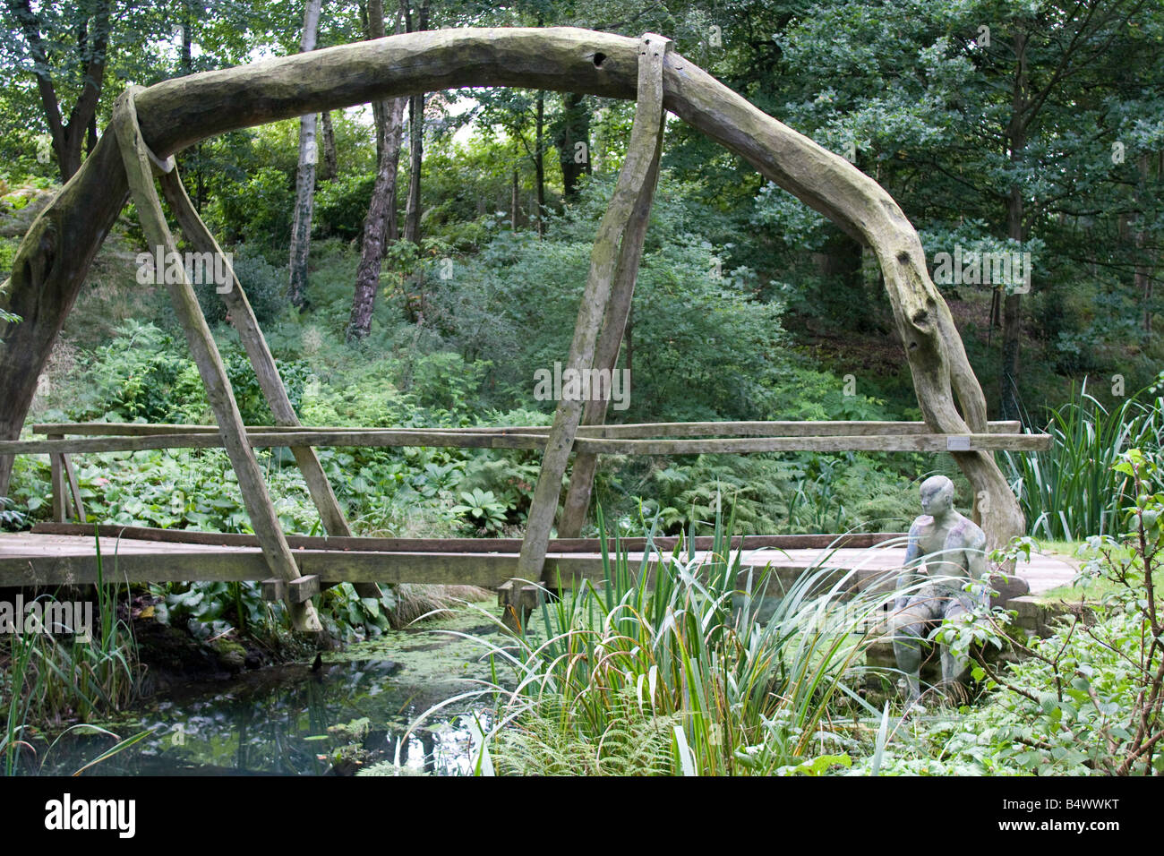 Grüne Eiche Brücke über Garten Wasserspiel mit Lifesize männliche Figur aus Bronze. Stockfoto