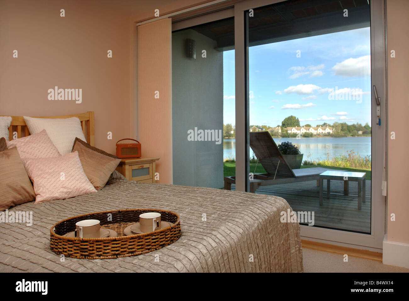 EIN SCHLAFZIMMER MIT BALKON IN EINER AM WASSER WOHNUNG AUF DEM UNTEREN MÜHLE-ANWESEN IN DER NÄHE VON CIRENCESTER GLOUCESTERSHIRE UK Stockfoto