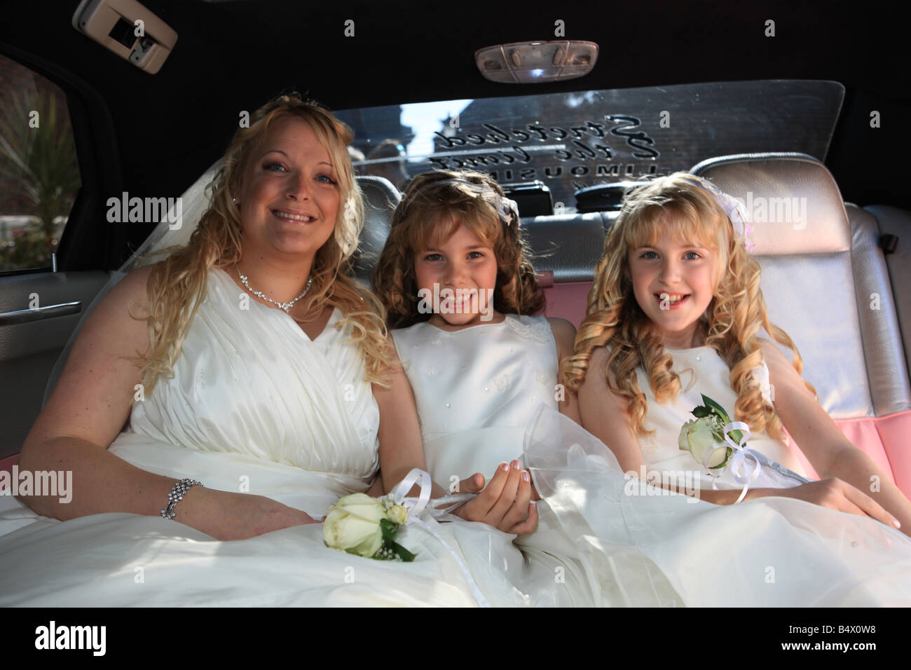 Braut und Brautjungfern, die Ankunft in einer rosa gestreckten Limousine für die Trauung Stockfoto