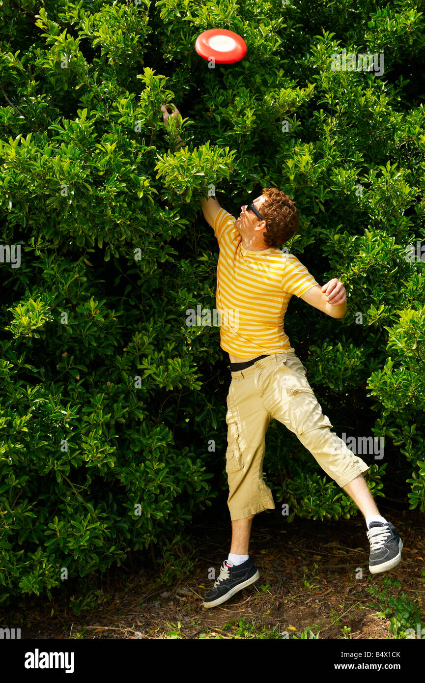 Junger Mann springen, um eine Frisbee zu erreichen Stockfoto