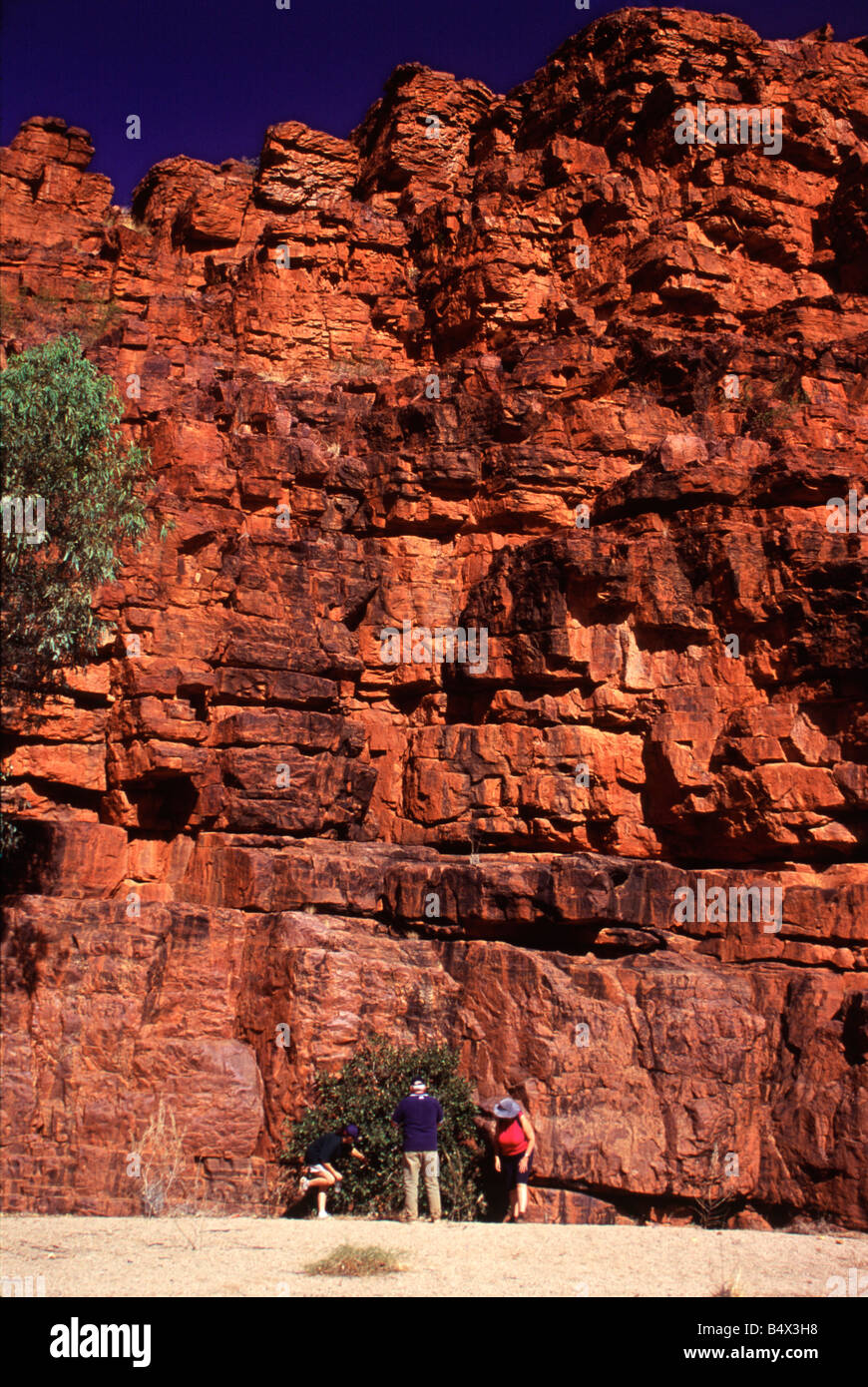 Drei Touristen an der Basis eine gigantische Felswand Trephina Gorge, Eastern Macdonnell Ranges, Alice Springs Stockfoto