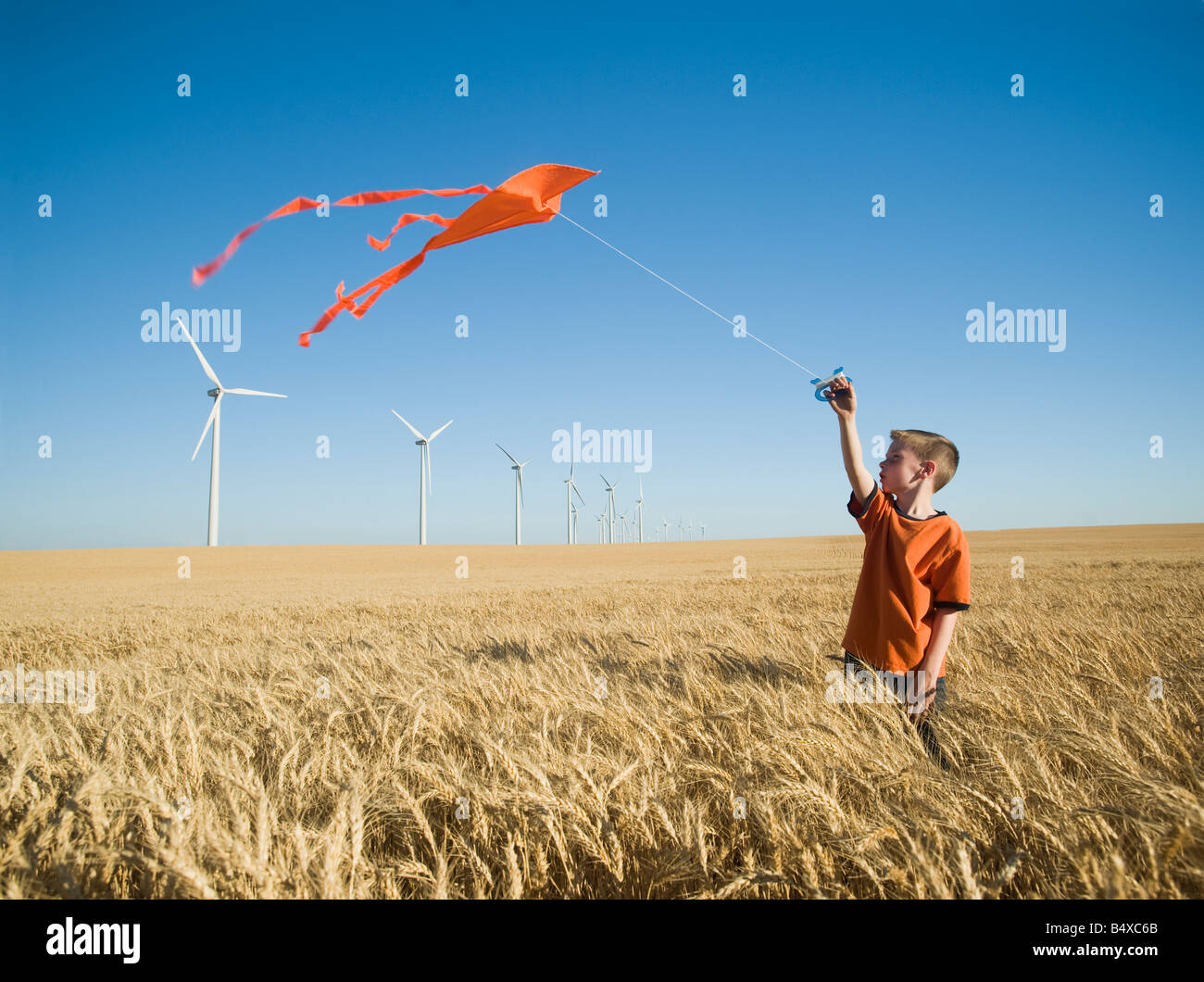 Junge läuft mit Kite am Windpark Stockfoto