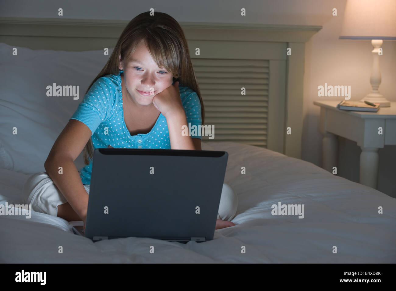 Mädchen mit Laptop am Bett Stockfoto