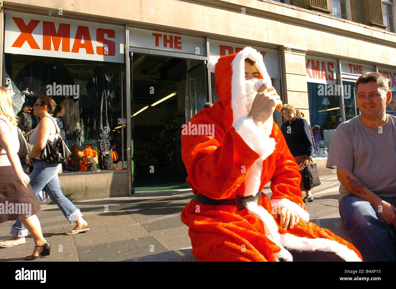 Eis und Santa Claus ungewöhnliche Kombination Student Matthew Weightman nimmt eine Verschnaufpause vom Einkaufen für Weihnachtsschmuck auf Grainger St an einem Sonnentag September als Shopper, die Eddie Allison blickt auf Stockfoto