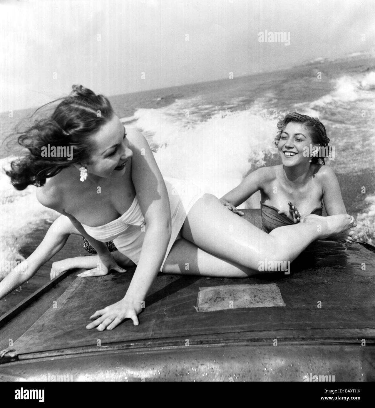 Shirley Ohman und Pau Barker an Brighton Sommer Urlaub August 1954 2 junge Frauen Plantschen im Meer in ein Boot der 1950er Jahre Baden Kostüme Spaß in der Sonne Stockfoto
